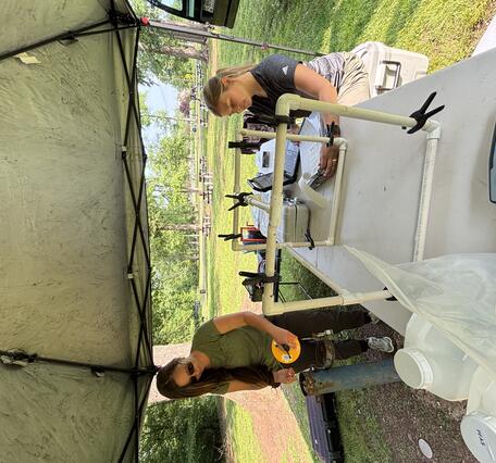 Two USGS Scientists drawing water samples from a well to prepare them for the lab