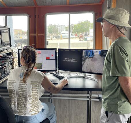 Two people looking at computer screens with data and dock images on them