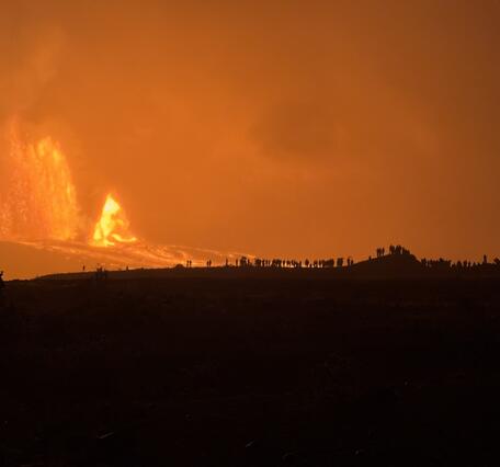 Color photograph of lava fountain with people silhouetted by the glow