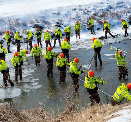 A photo composite of 35 images showing hydrologic technicians breaking up an ice and measuring streamflow.