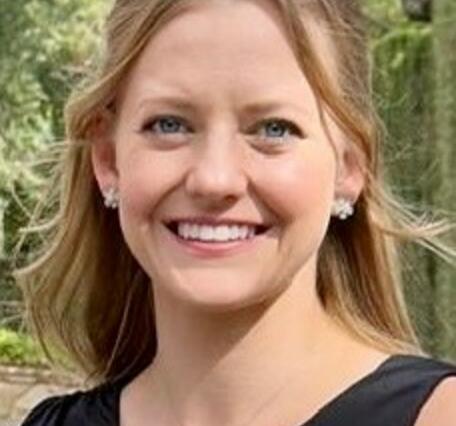 blonde-haired woman smiling wearing black shirt with plants in the background