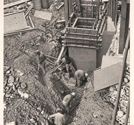 Men digging a trench from the base of the new gage towards the river 