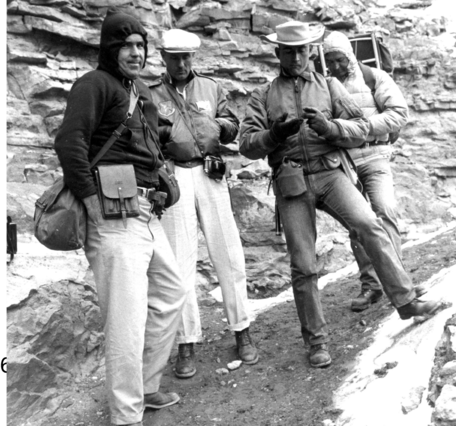 Four men in cold gear standing in front of a rock outcrop