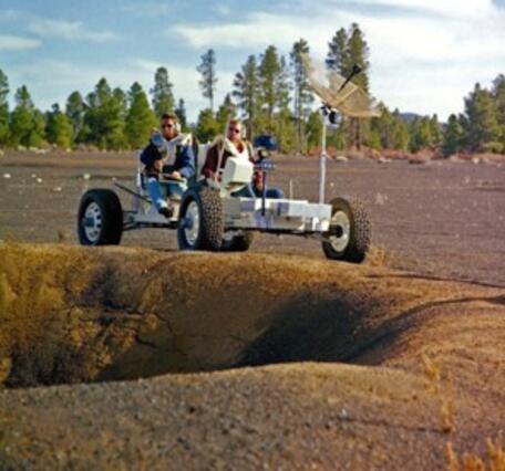 Photo of astronauts driving a lunar rover in the Cinder Lake Crater Field