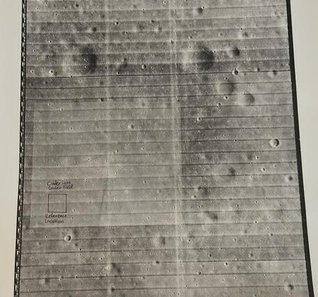 Photo of a printed image of the lunar surface with a small box over a region labeled "Cinder Lake Crater Field Reference"
