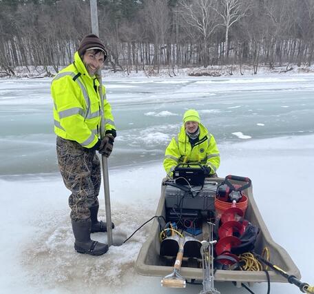 Scientists taking a reading of the flow under the ice on the river