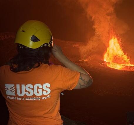 Color photograph of scientist monitoring a volcanic eruption