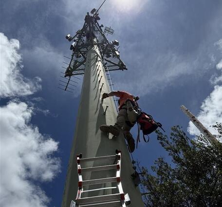 Color photograph of field engineer climbing tower
