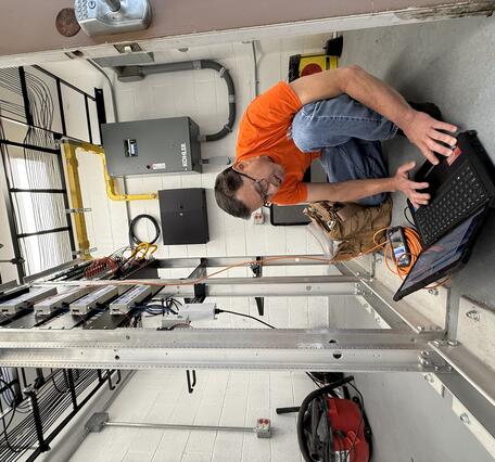 Color photograph of field engineer checking laptop