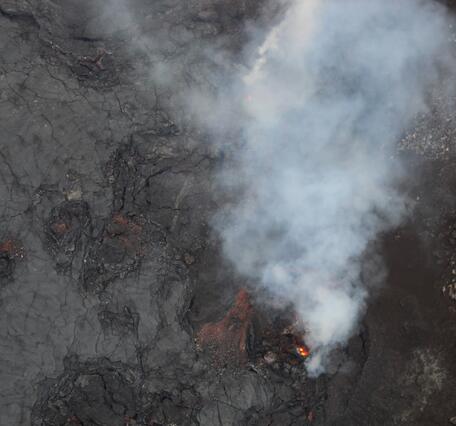 Color photograph of volcanic vent with lava visible within
