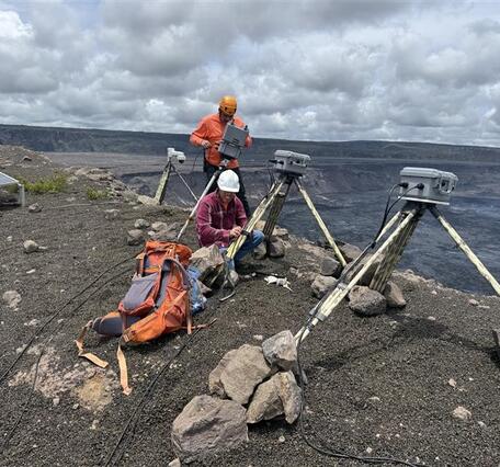 Color photograph of scientist installing webcameras on rim of volcano