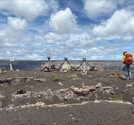 Color photograph of scientist near volcano monitoring equipment