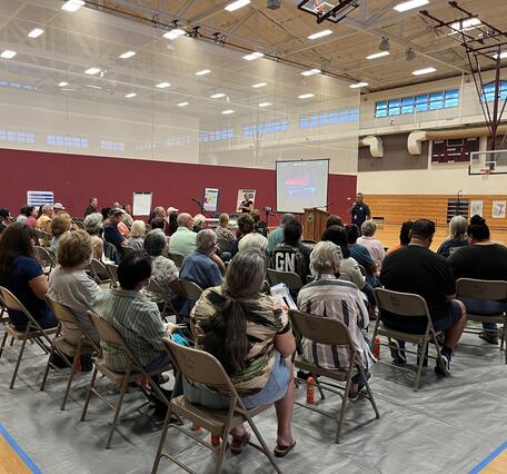 Color photograph of person presenting to an audience in a gymnasium