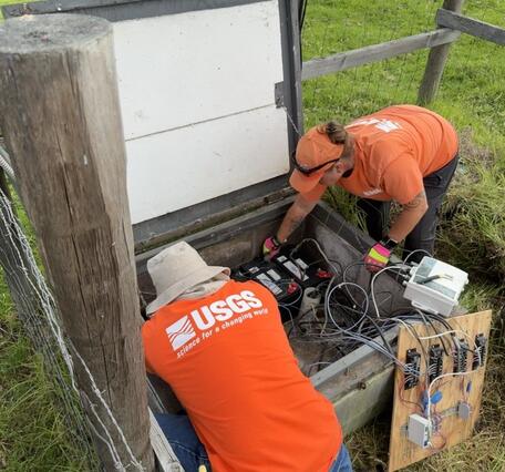 Color photograph of field engineers maintaining volcano monitoring instrumentation