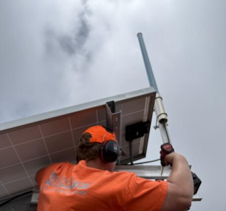 Color photograph of field engineer working on antenna at volcano monitoring site