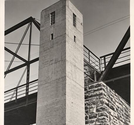 A concrete tower to house the gage stands next to the footer of the bridge