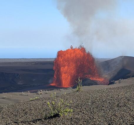 Orange and incandescent lava fountain erupting from a crater