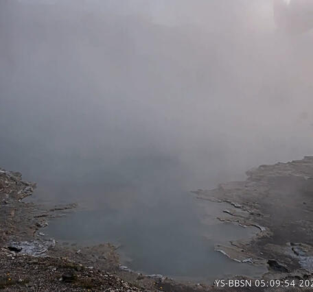steaming blue pool in low-light dawn conditions with an explosive steam plume in the background