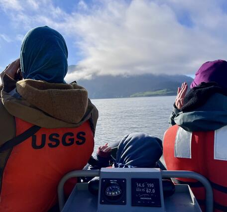 Two people wearing orange life jackets facing away from the camera.