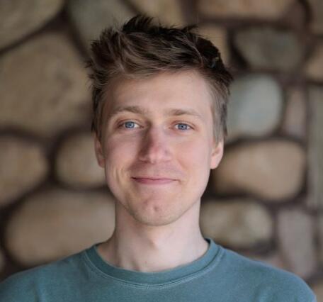 Man smiling while standing in front of stone wall background