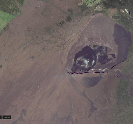 Color satellite image of a caldera at the summit of a volcano with deposits of different ages appearing different in color