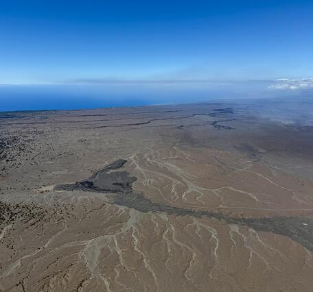 Color photograph of volcanic landscape and ocean in the distance