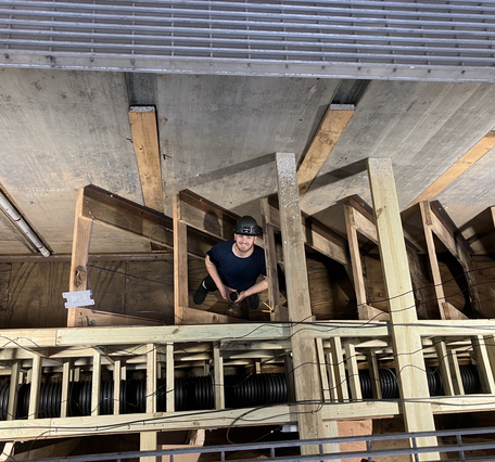 Young man wearing a hard hat stands in the wooden baffles of a de-watered fish ladder