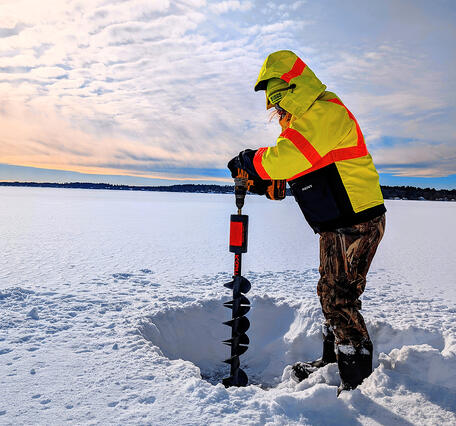 Technician bores a hole in a frozen lake to take water quality samples on Long Pond, Lakeville, MA.