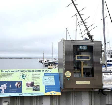 A streamgage next to a sign on the water.