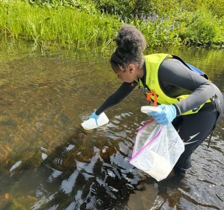 A researcher stands in a stream collected water samples.