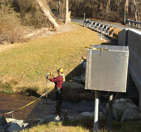 Measuring streamflow in a small stream near a bridge and streamgage.