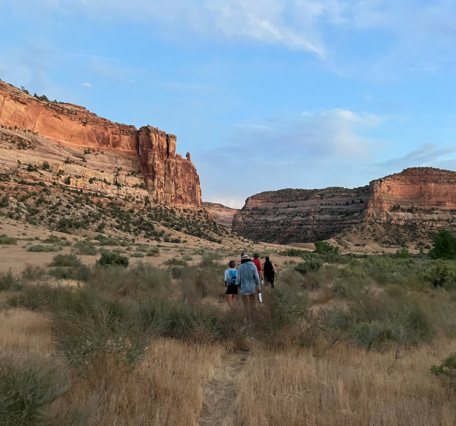 People walk in grassland towards canyons