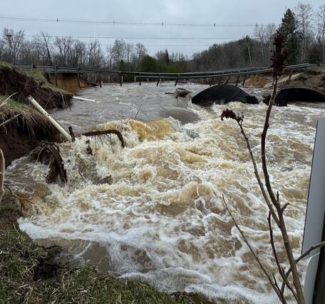 Washed out bridge over raging flood waters on a gray day