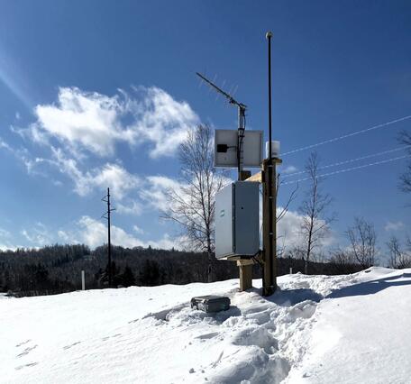 Streamgage surrounded by snow on a sunny winter day