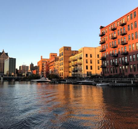 Sunset illuminating buildings in a city with a river in foreground