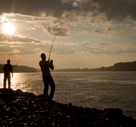 Two people fishing at sunset.