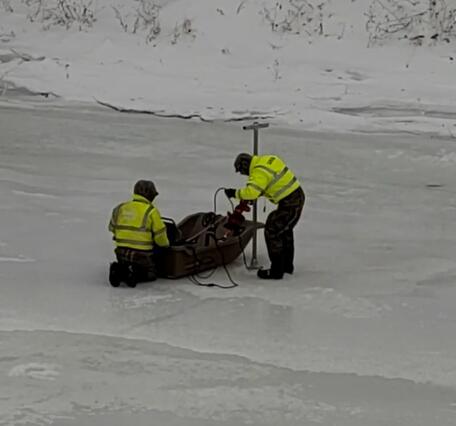 Two Scientists working off of a sled on a frozen river 