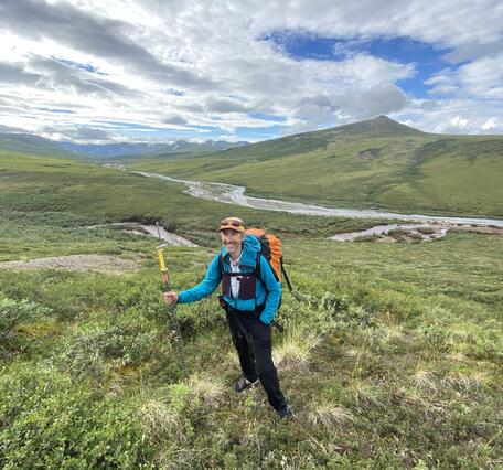 A man in a blue jacket standing in front of a river.