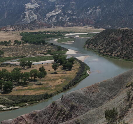 panoramic, aerial shot of a river bending through shrublands and mountains