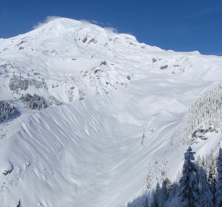 A snow-covered mountain peak with a blue sky in the background