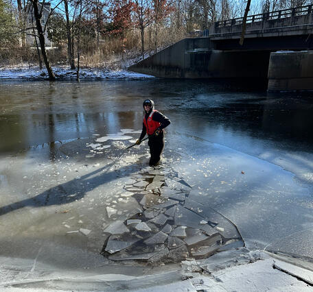 Scientist breaking up and wading through ice covered river