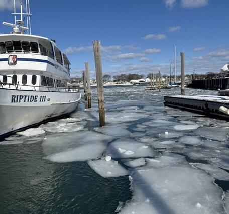 Chunks of ice on top of water near a dock and boat.