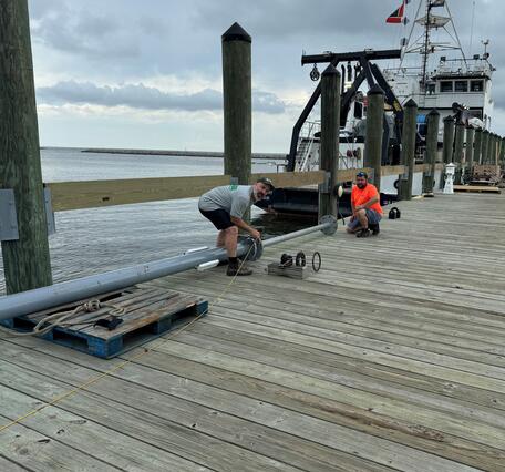Two people on dock working with coring equipment