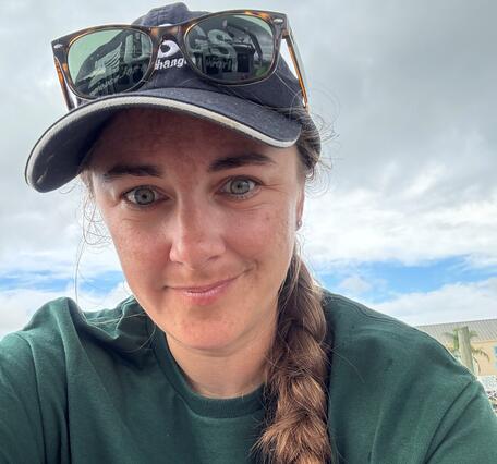 woman in USGS hat and shirt smiling outside