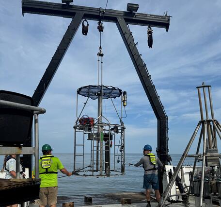 Three people on deck of ship working with mega multicorer