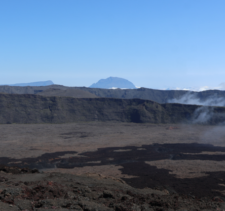 rocky cliffs with clouds and mountain visible in the background