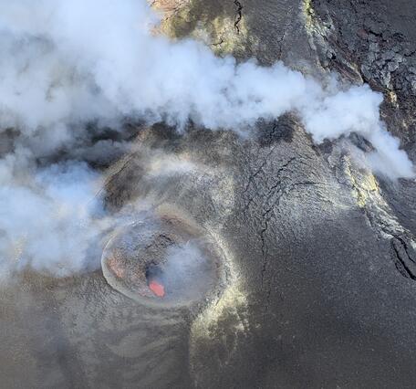 Color photograph looking down into a volcanic vent with magma visible inside it