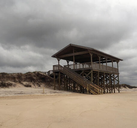 A pavilion or lookout deck that was previously on a dune, now with exposed support pilings after a series of storms