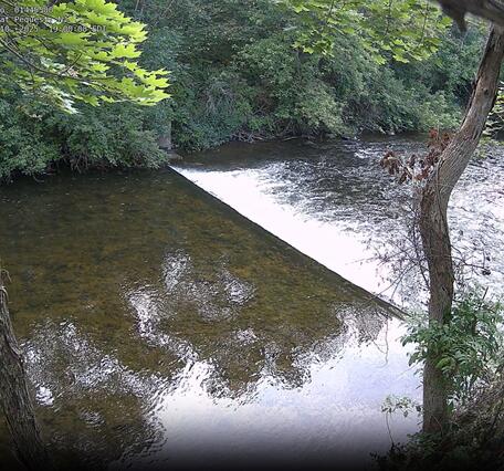 Looking downstream from a high vantage point as the river flows over a weir creating turbulence  downstream