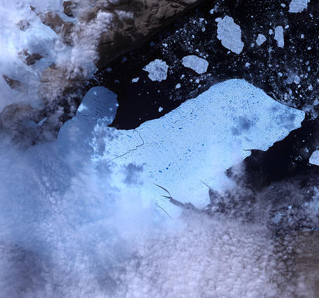 Satellite image of a glacier with chunks of ice in the water around the end of it